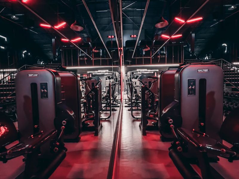 Spacious dark gym interior with neon orchid light stripes